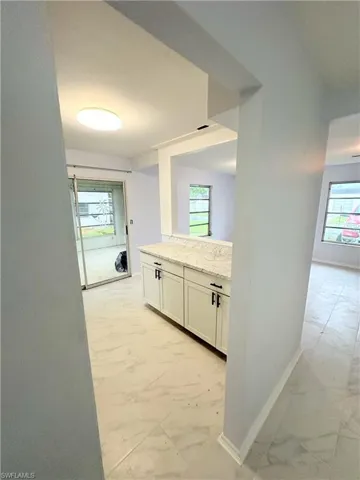 Kitchen featuring light tile patterned flooring, a healthy amount of sunlight, and white cabinets