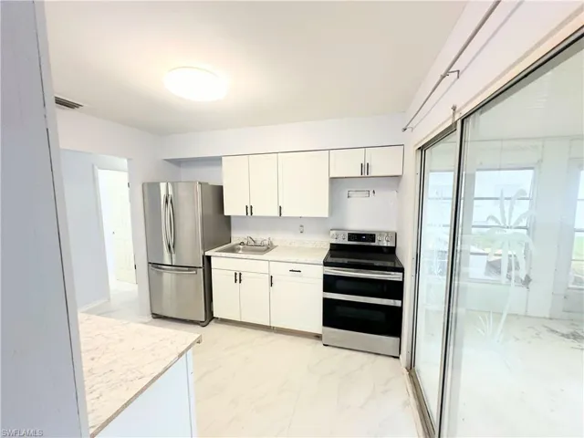 Kitchen featuring sink, white cabinetry, appliances with stainless steel finishes, and light tile patterned floors
