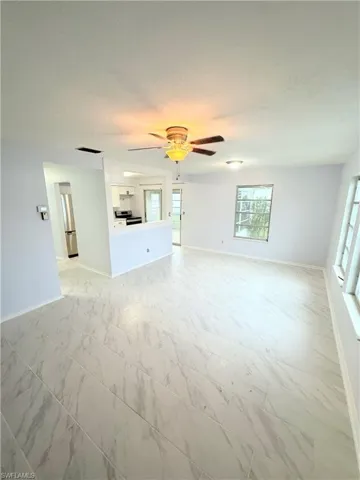 Unfurnished living room with ceiling fan and light tile patterned floors