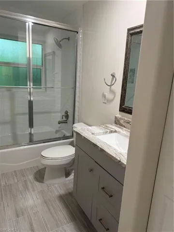Full bathroom featuring enclosed tub / shower combo, vanity, and toilet