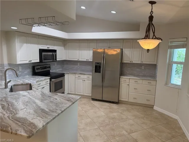 Kitchen with tasteful backsplash, light tile patterned floors, a sink, stainless steel appliances, and light stone counters