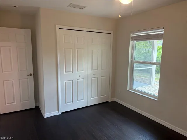 Unfurnished bedroom featuring a closet, visible vents, baseboards, and dark wood finished floors