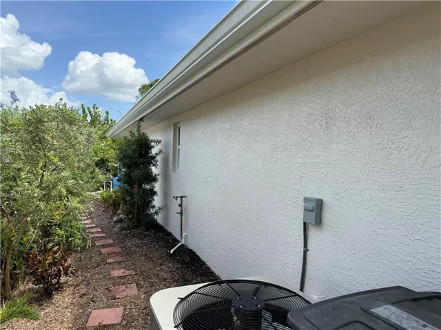 View of side of home with stucco siding and cooling unit