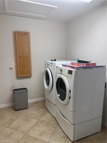 Clothes washing area with laundry area, baseboards, and washer and clothes dryer