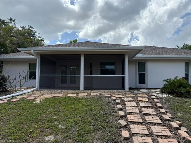 Back of property featuring roof with shingles, a sunroom, and stucco siding