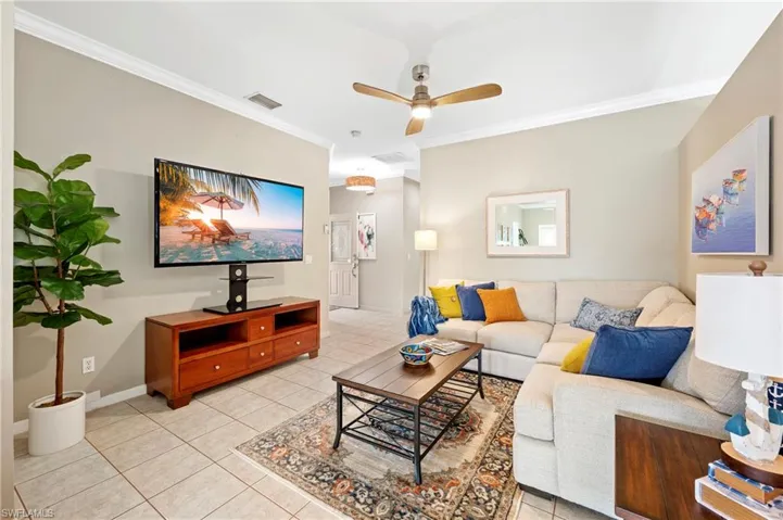 Living room with crown molding, a ceiling fan, and light tile patterned floors