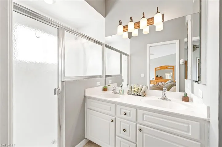 Full bath featuring double vanity, a stall shower, and connected bathroom