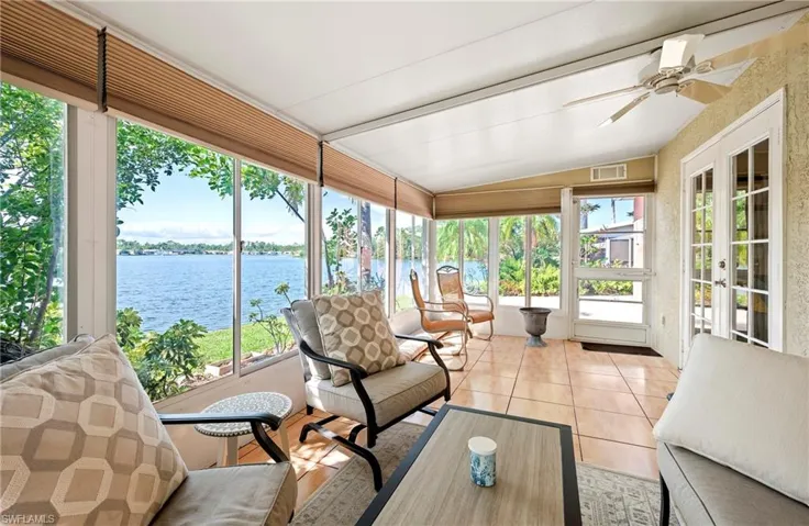 Sunroom with a water view, lofted ceiling, healthy amount of natural light, french doors, and a ceiling fan