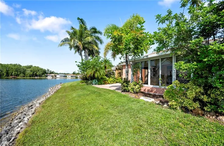 View of grassy yard featuring a water view and a sunroom