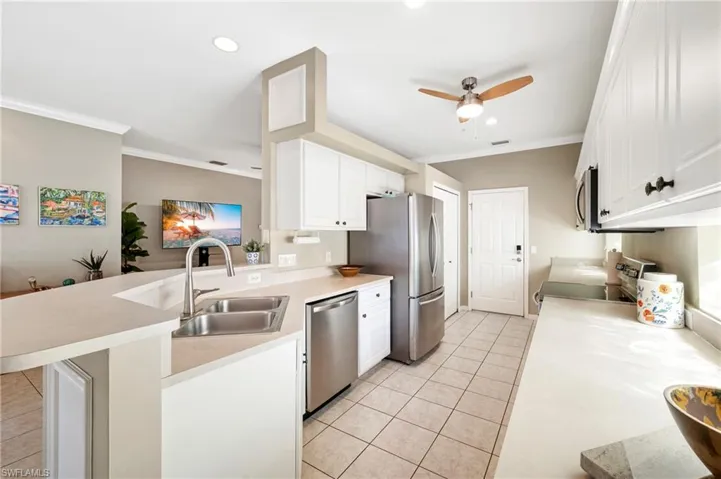 Kitchen featuring a peninsula, light tile patterned floors, crown molding, white cabinets, and ceiling fan