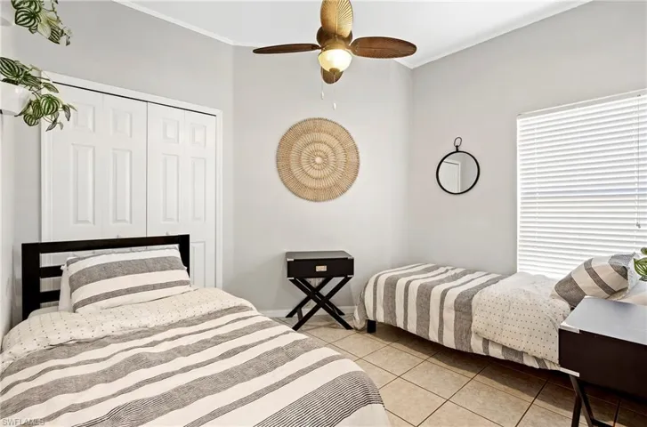 Bedroom with light tile patterned floors, crown molding, a closet, and a ceiling fan
