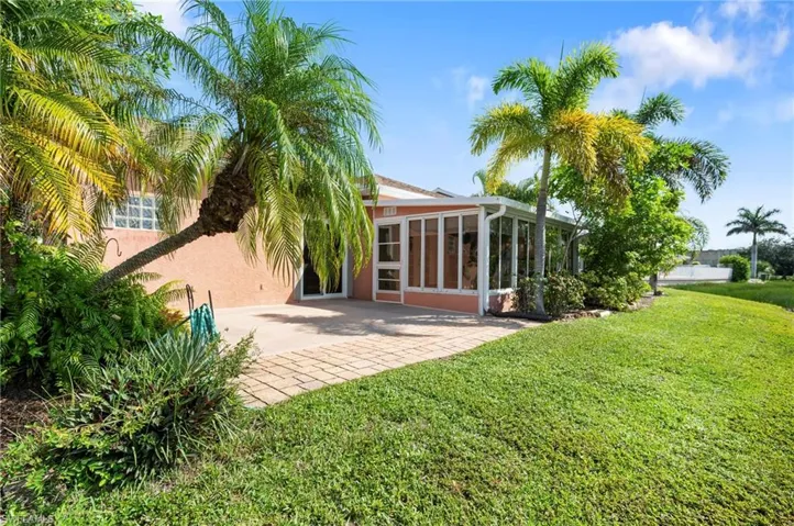 Back of house with a sunroom, stucco siding, a yard, and a patio area