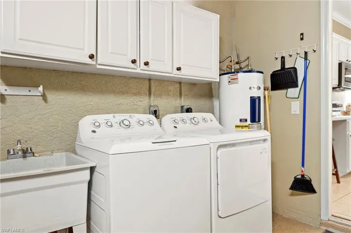Washroom with washing machine and dryer, water heater, and cabinet space