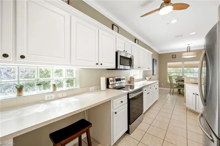 Kitchen featuring appliances with stainless steel finishes, white cabinets, crown molding, light countertops, and light tile patterned flooring