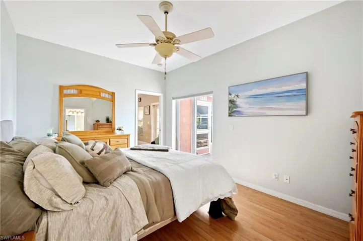 Bedroom with wood finished floors, a ceiling fan, and connected bathroom