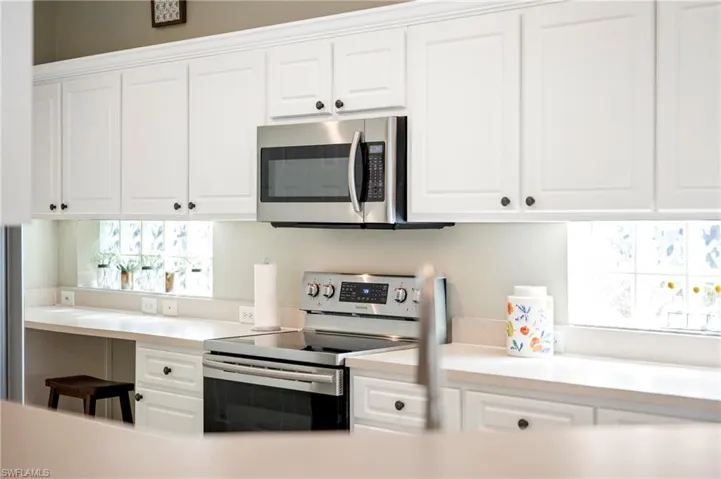 Kitchen with stainless steel appliances, white cabinetry, and light countertops