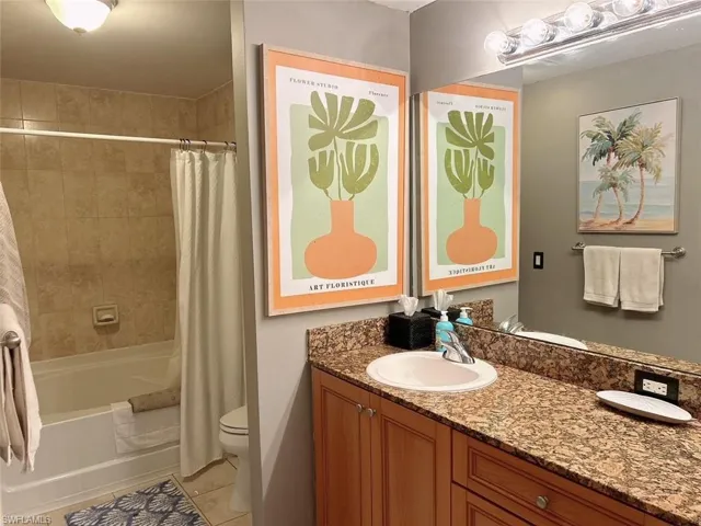 Full bathroom with tile floors, shower / tub combo with curtain, toilet, and large vanity