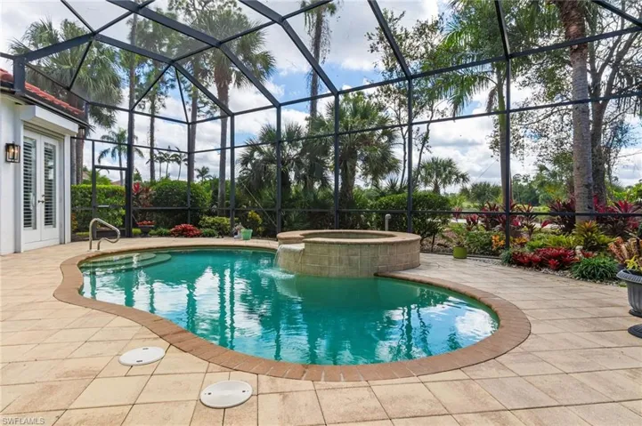 View of pool with glass enclosure, a patio, a sunroom, and a pool with connected hot tub