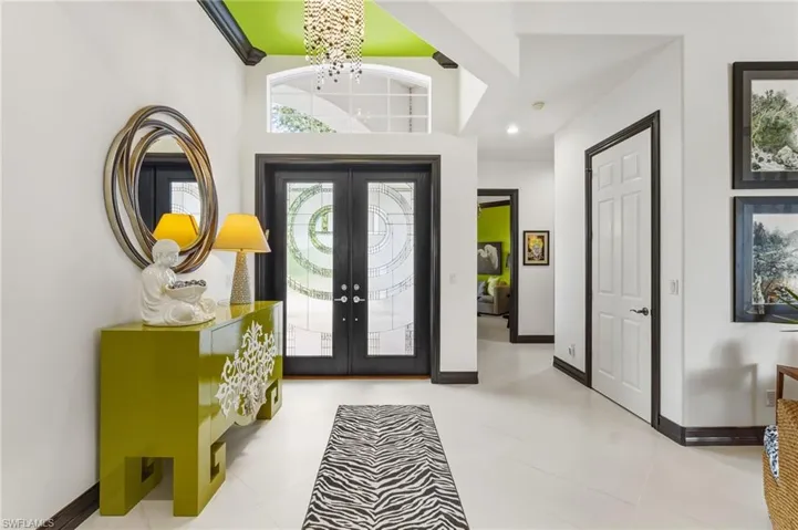 Tiled entrance foyer with french doors, a chandelier, and recessed lighting