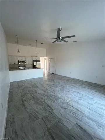 Unfurnished living room with a ceiling fan and vaulted ceiling