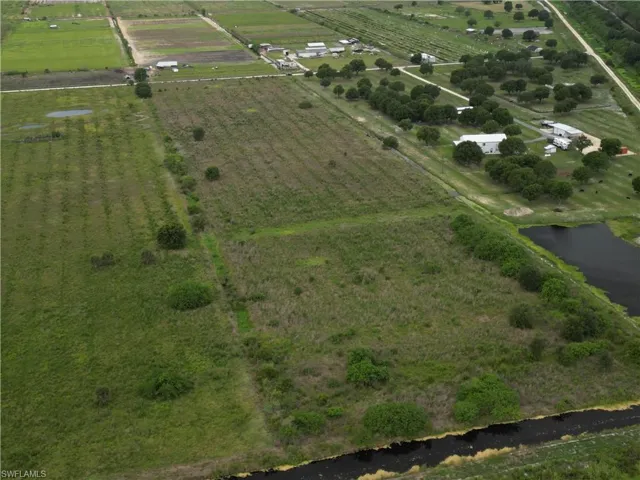 Expansive agricultural land featuring a water canal, adjacent cultivated fields, and a scattered tree line