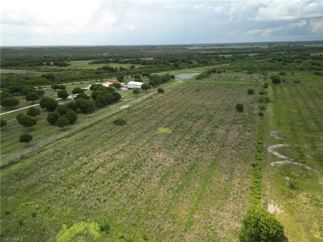 Expansive acreage featuring multiple structures, a pond, and mature tree lines