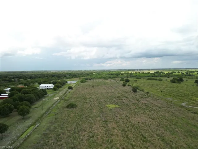 Expansive agricultural land featuring a waterway, mature trees, and visible structures