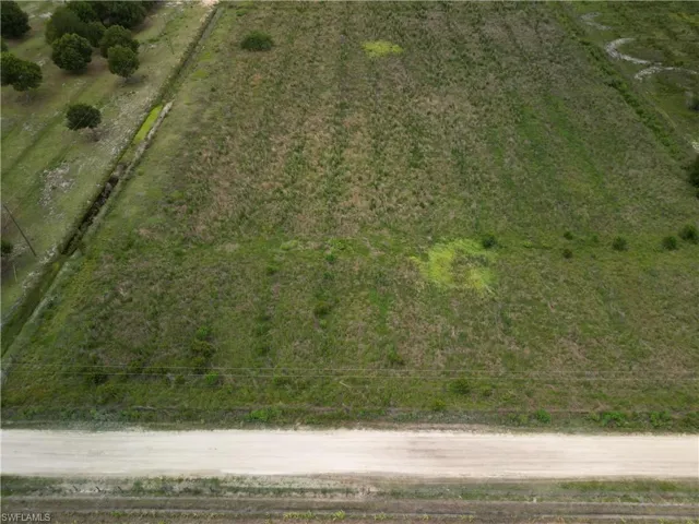 Expansive land parcel featuring natural grasses and bordering a dirt road