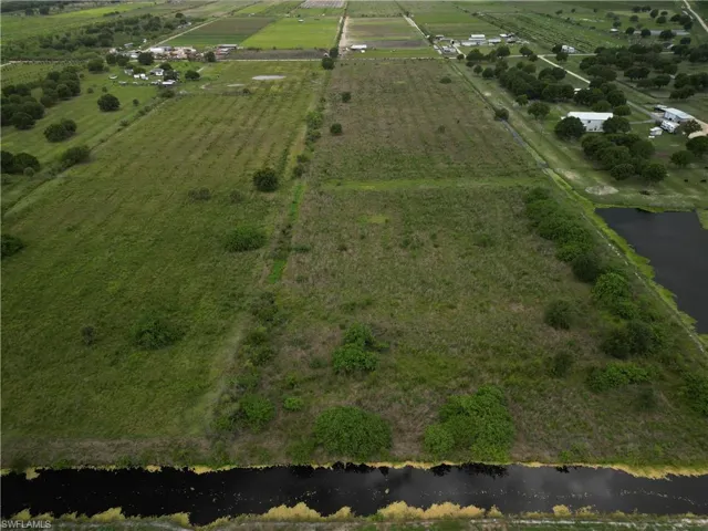 Expansive agricultural land featuring a waterway bordering one edge and rows of cultivated fields