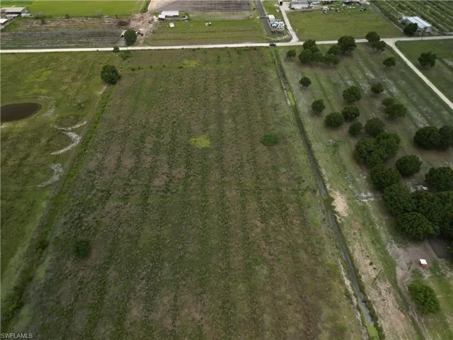 Expansive agricultural land featuring a visible irrigation canal and a scattered tree line