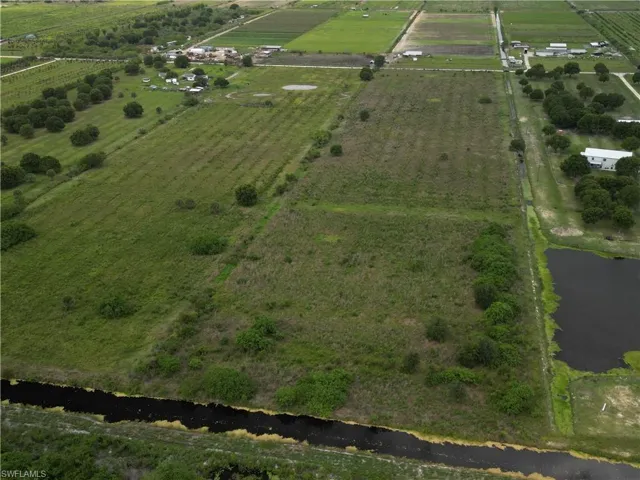 Expansive acreage featuring multiple cultivated fields, mature trees, and a visible pond