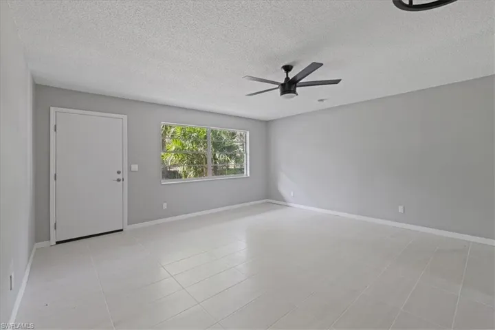 Unfurnished room with a textured ceiling, ceiling fan, and light tile patterned flooring