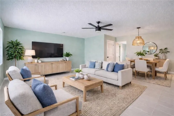 Tiled living area featuring a ceiling fan and a textured ceiling