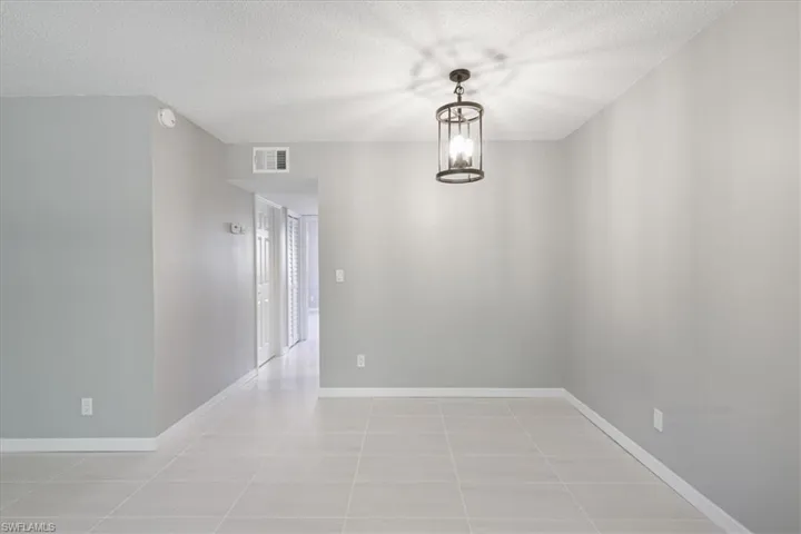 Unfurnished room featuring a textured ceiling, a chandelier, and light tile patterned floors