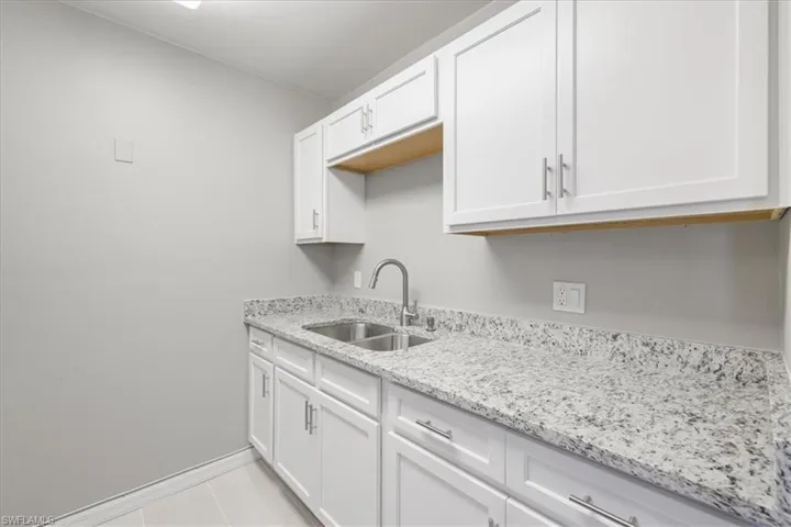 Kitchen featuring light stone countertops and white cabinetry