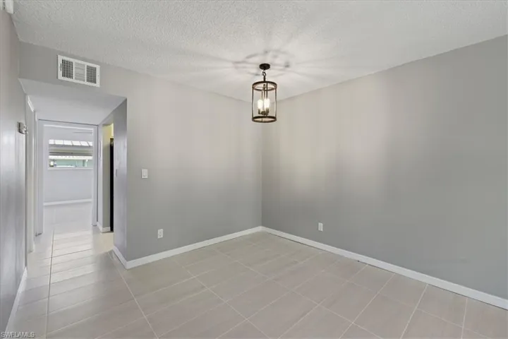 Unfurnished dining area featuring a textured ceiling, a chandelier, and light tile patterned floors