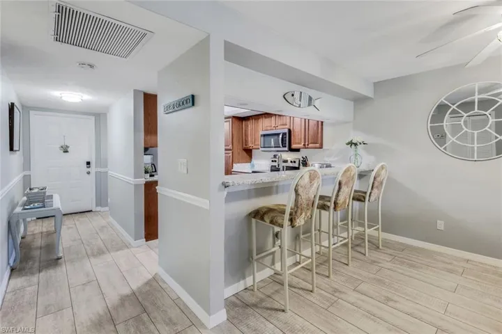 Kitchen with stainless steel microwave, light wood finished floors, stove, and brown cabinetry