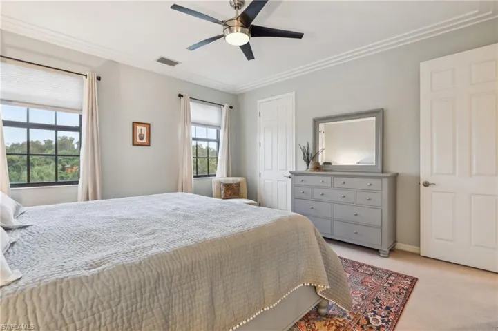 Bedroom featuring ceiling fan, light colored carpet, and ornamental molding