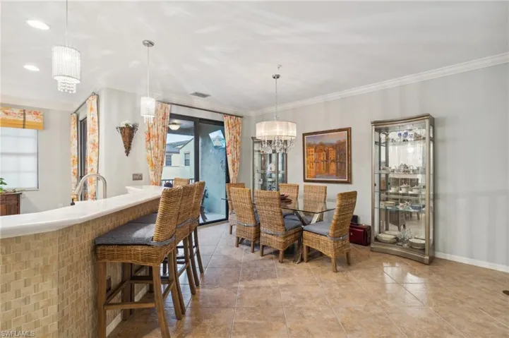 Tiled dining space featuring a wealth of natural light, a chandelier, and ornamental molding