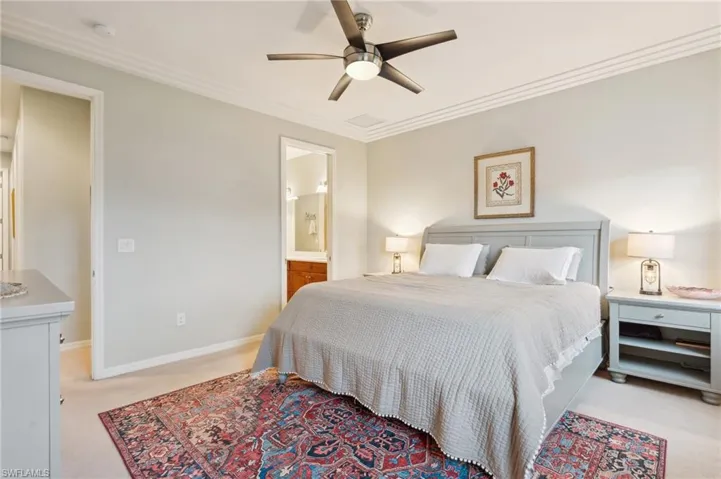 Carpeted bedroom featuring crown molding, ceiling fan, and connected bathroom