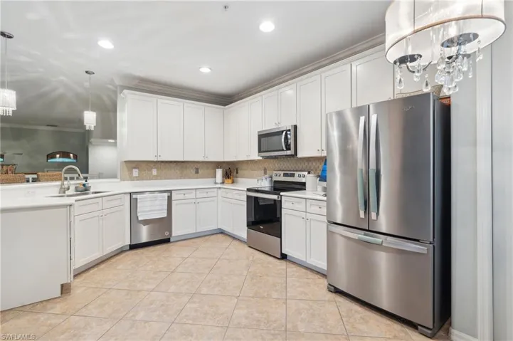 Kitchen featuring decorative light fixtures, light tile patterned floors, appliances with stainless steel finishes, sink, and white cabinetry