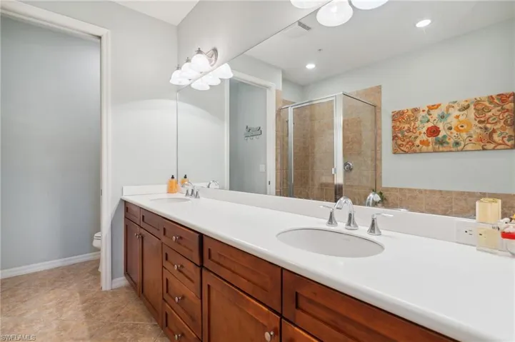 Bathroom with vanity, toilet, an enclosed shower, and tile patterned floors