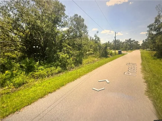 View of asphalt street featuring view of wooded area