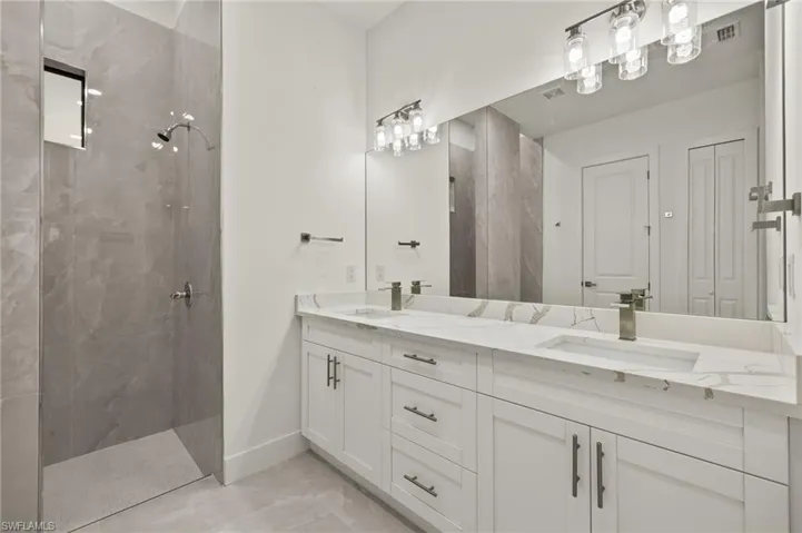 Primary Bathroom with tiled walk -in shower, double sink vanity with quartz counter tops, toilet room.