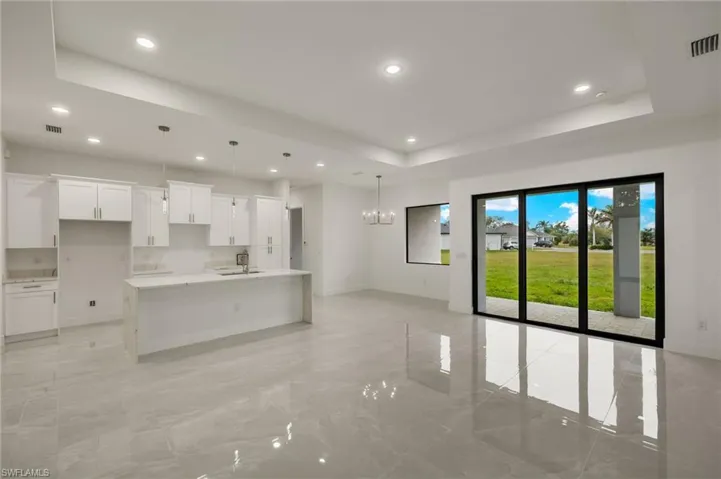 Kitchen with elegant lighting, a waterfall Quartz island, 42"  white cabinetry, tray ceiling
