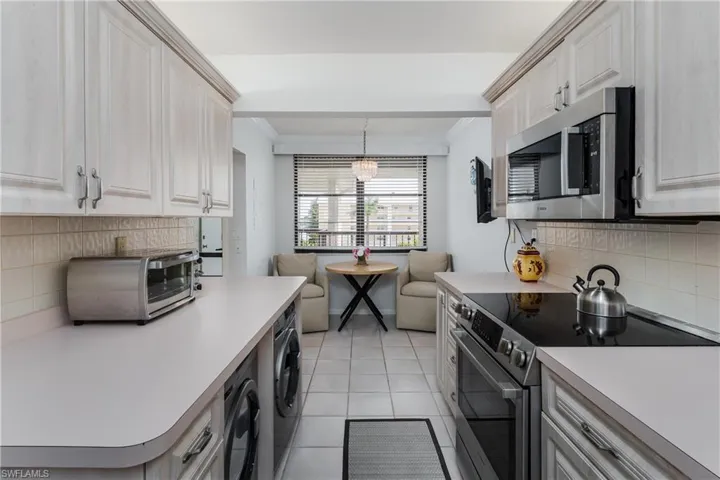 Kitchen featuring  tile backsplash, stainless steel appliances, washing machine and dryer,
