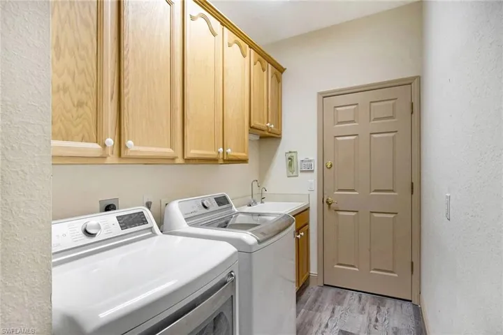 Laundry room featuring cabinets, independent washer and dryer, light hardwood / wood-style floors, and sink