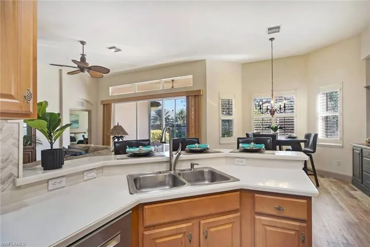 Kitchen featuring sink, kitchen peninsula, light hardwood / wood-style floors, decorative light fixtures, and ceiling fan with notable chandelier