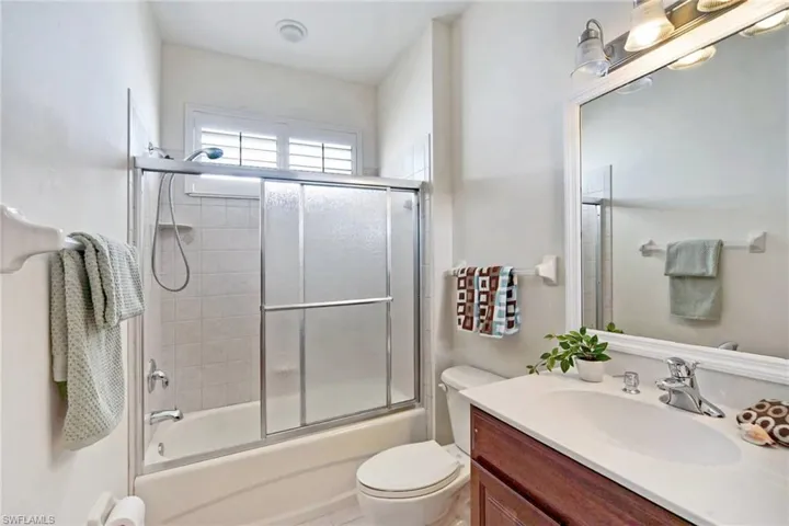 Full bathroom with combined bath / shower with glass door, vanity, and toilet