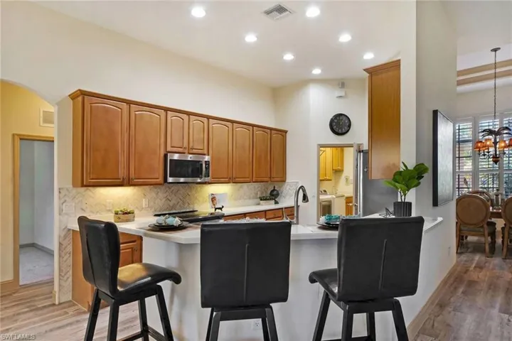 Kitchen featuring kitchen peninsula, decorative light fixtures, washer / dryer, a kitchen bar, and hardwood / wood-style flooring